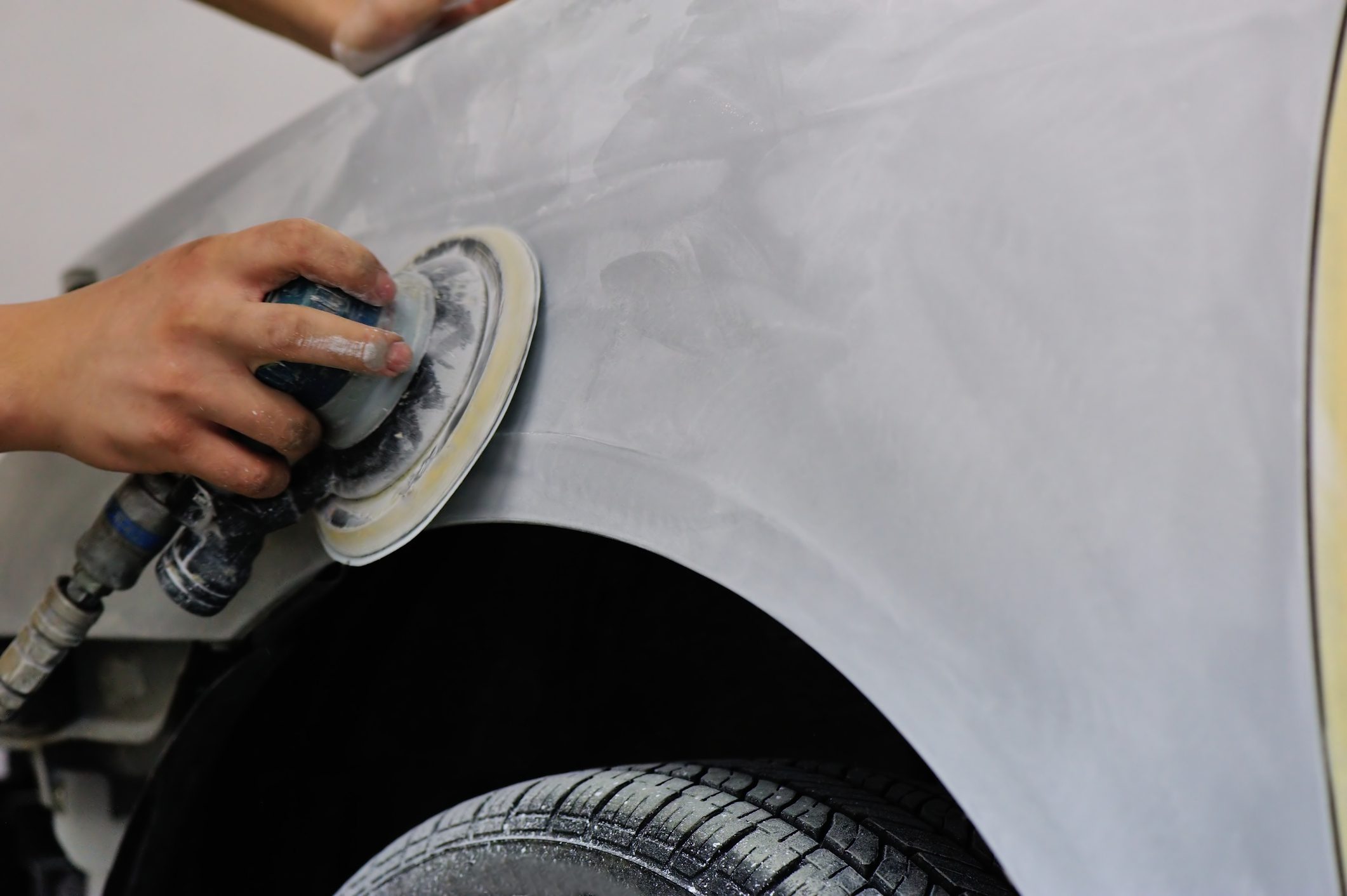 Car being polished with electric buffer.